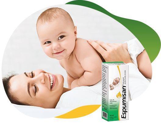 Two packs of Espumisan 100 mg/ml Emulsion in different sizes in the foreground, behind the big package is an illustrated lion. In the background there is a happy baby that lies on his smiling mother and looking curiously at the camera